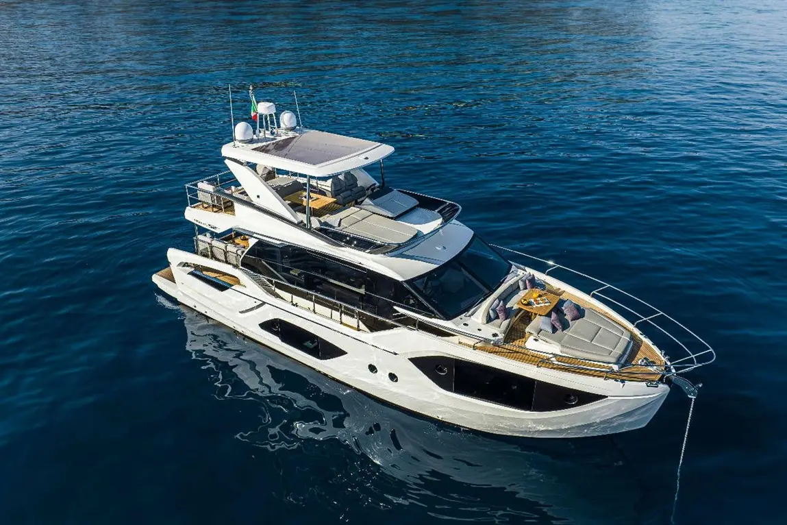 Luxurious white yacht with a spacious deck, moored on calm blue waters, featuring stylish seating and dining area.